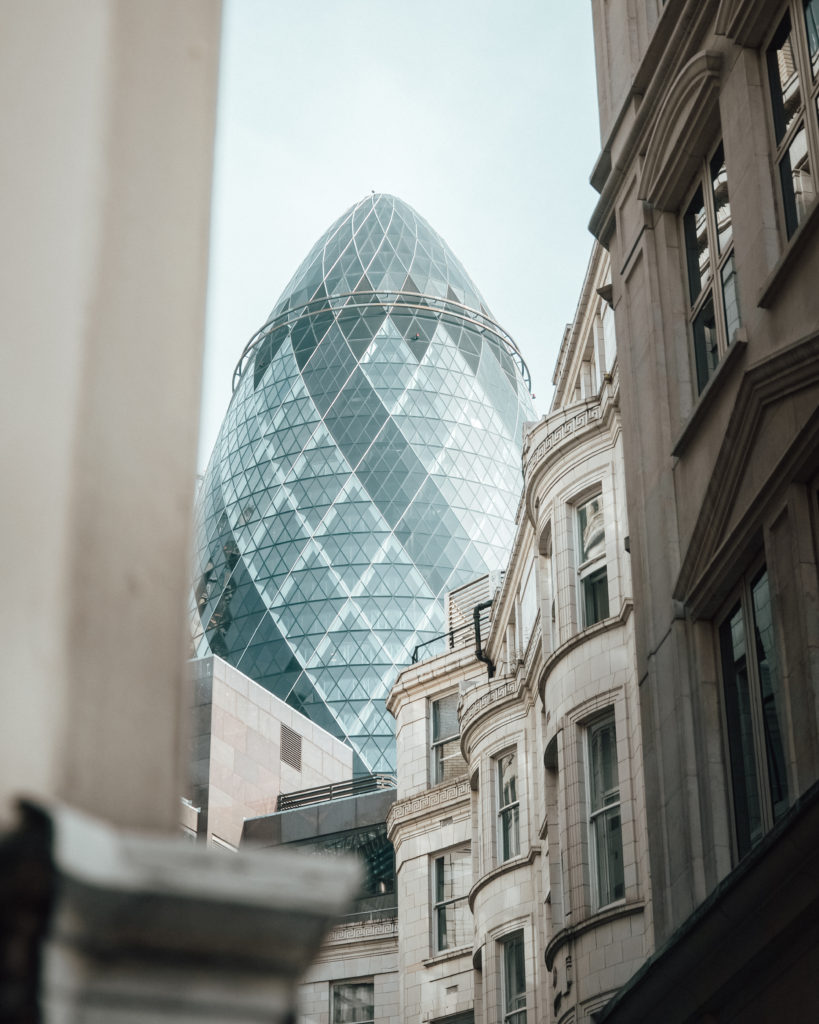 View of the Gherkin skyscraper through city of London streets