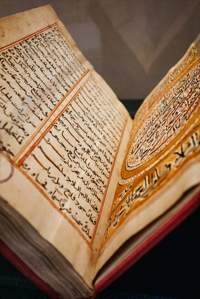 Open book displaying ink and watercolour illustrated Arabic script, National Museum of Oman
