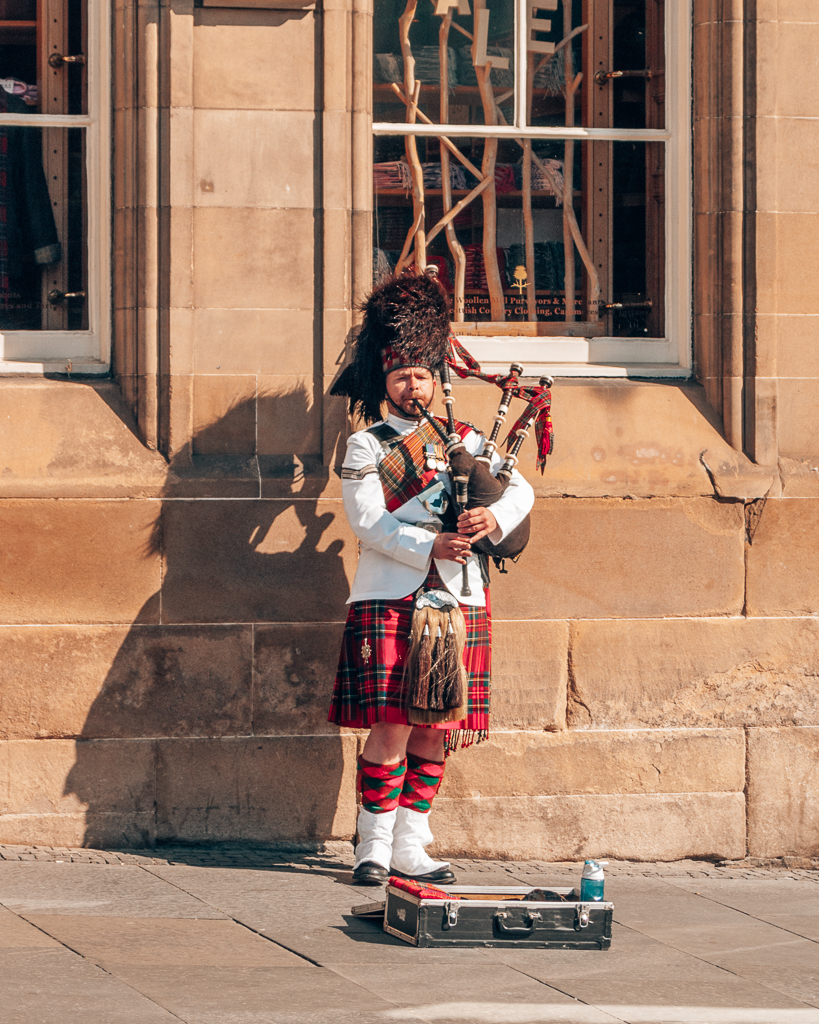 Man in red kilt and bearskin hat playing the bagpipes