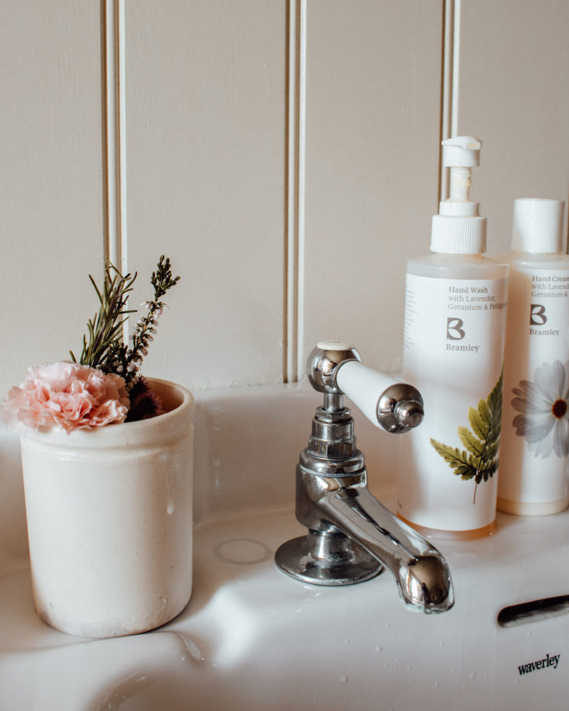Buttonhole flowers in a cup next to a tap on a sink