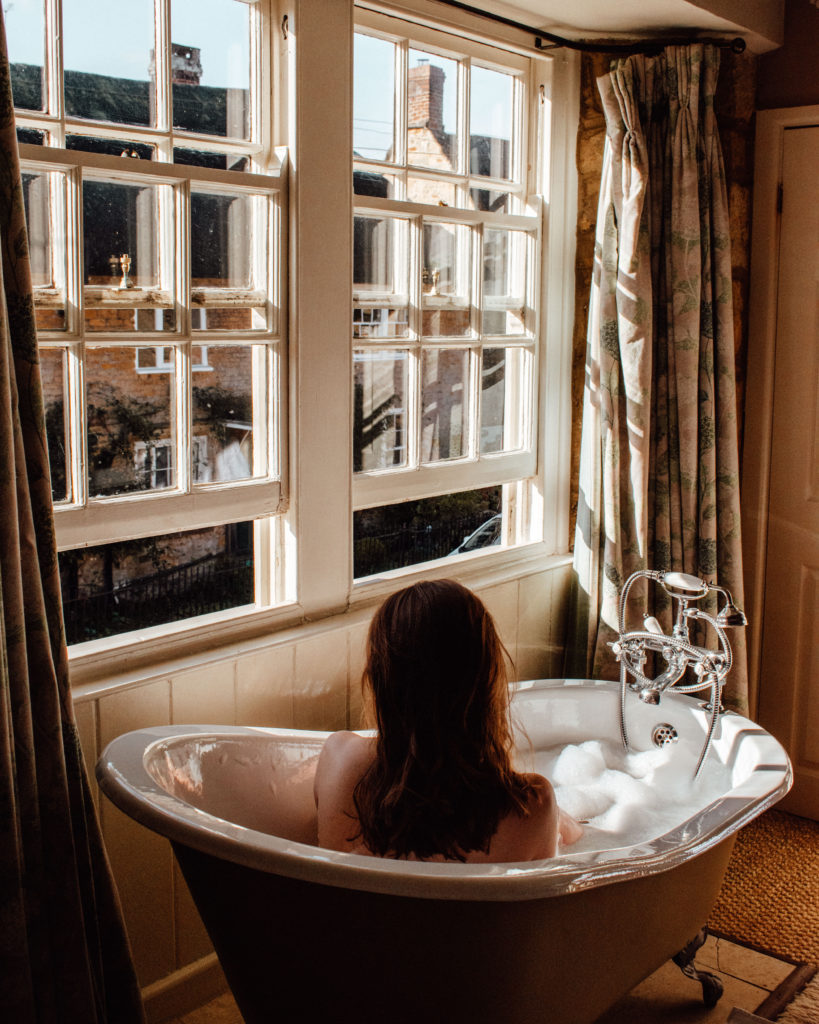 Woman in a bath by a sunny window