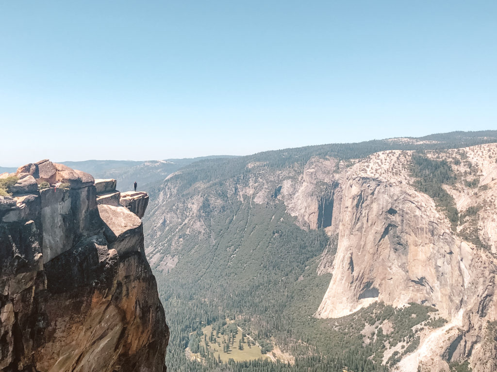 Woman standing on rock perched over steep cliff at Taft Point