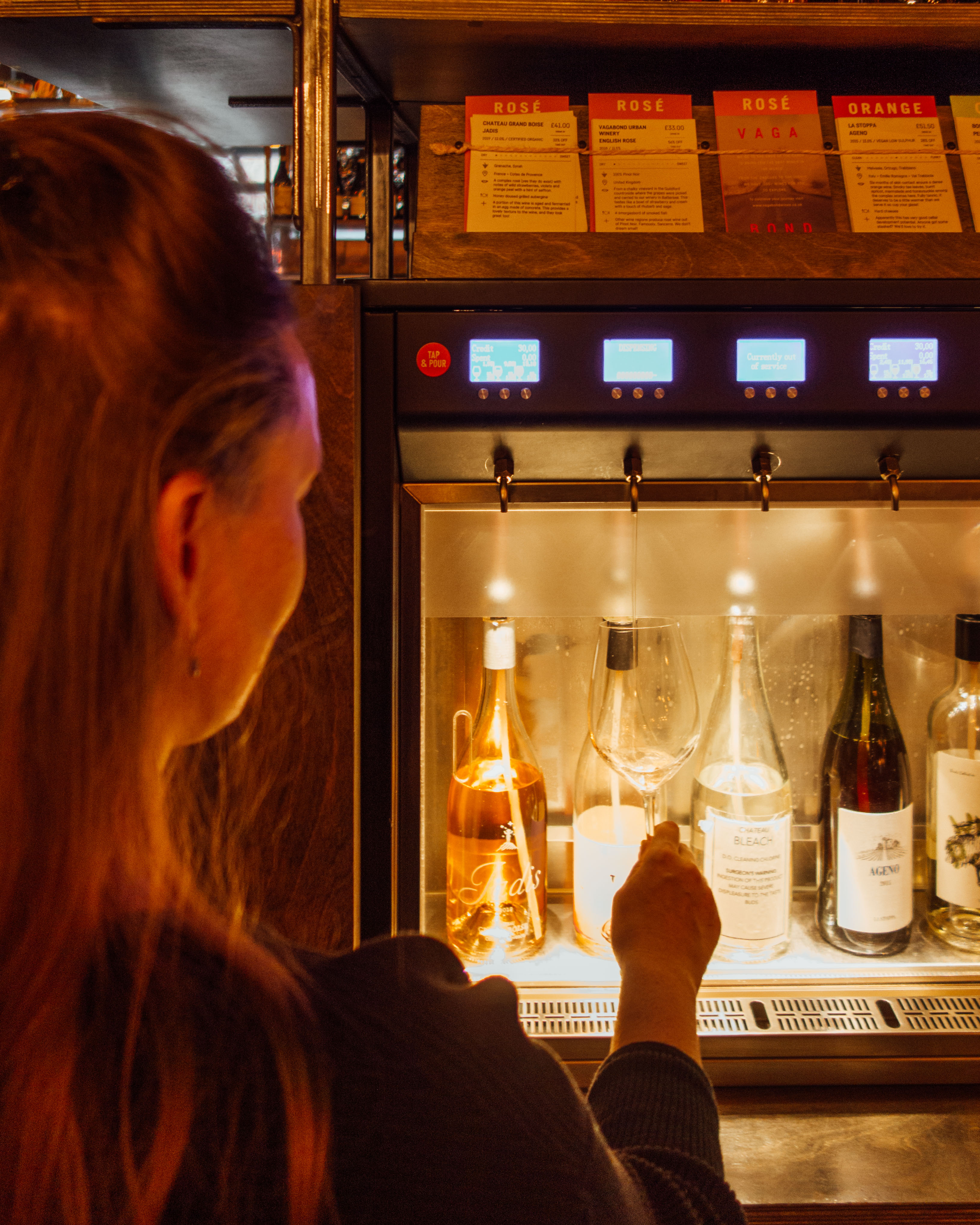 Woman getting wine from dispenser in Vagabound's Bar, London