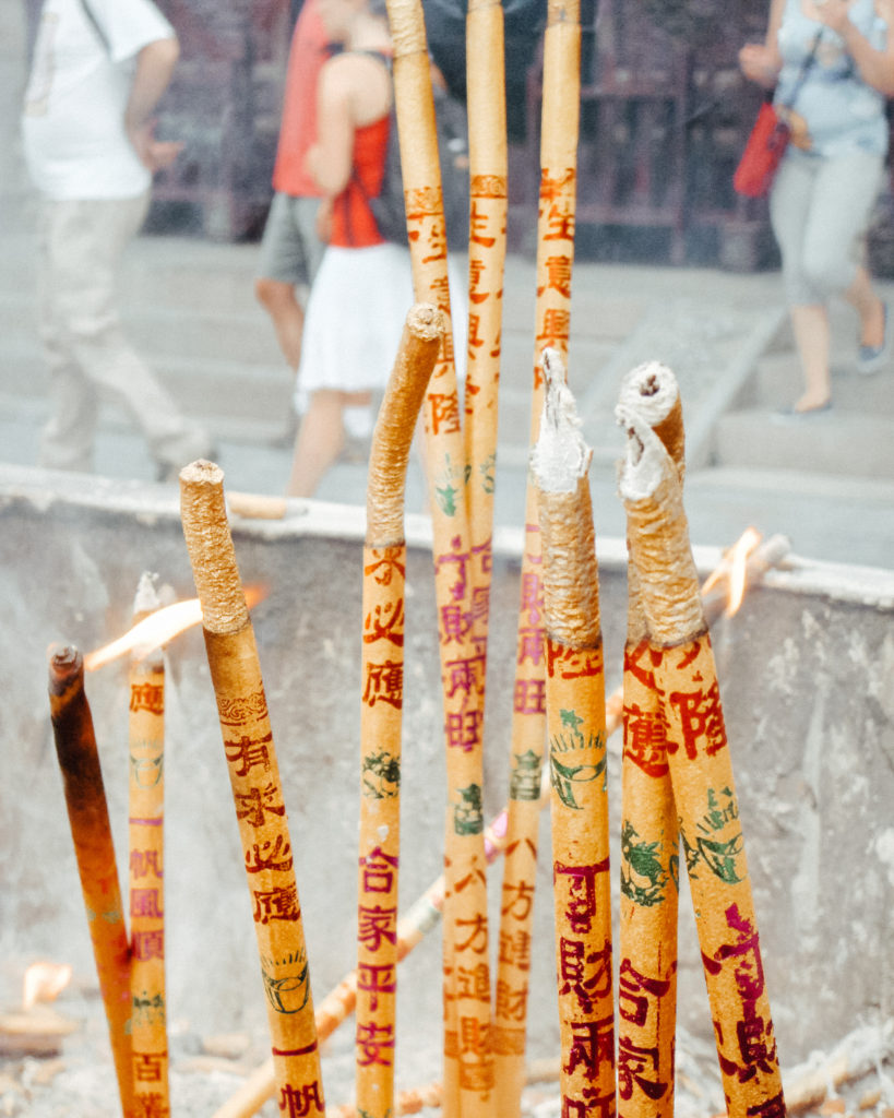 Burning incense and candles covered in Chinese calligraphy