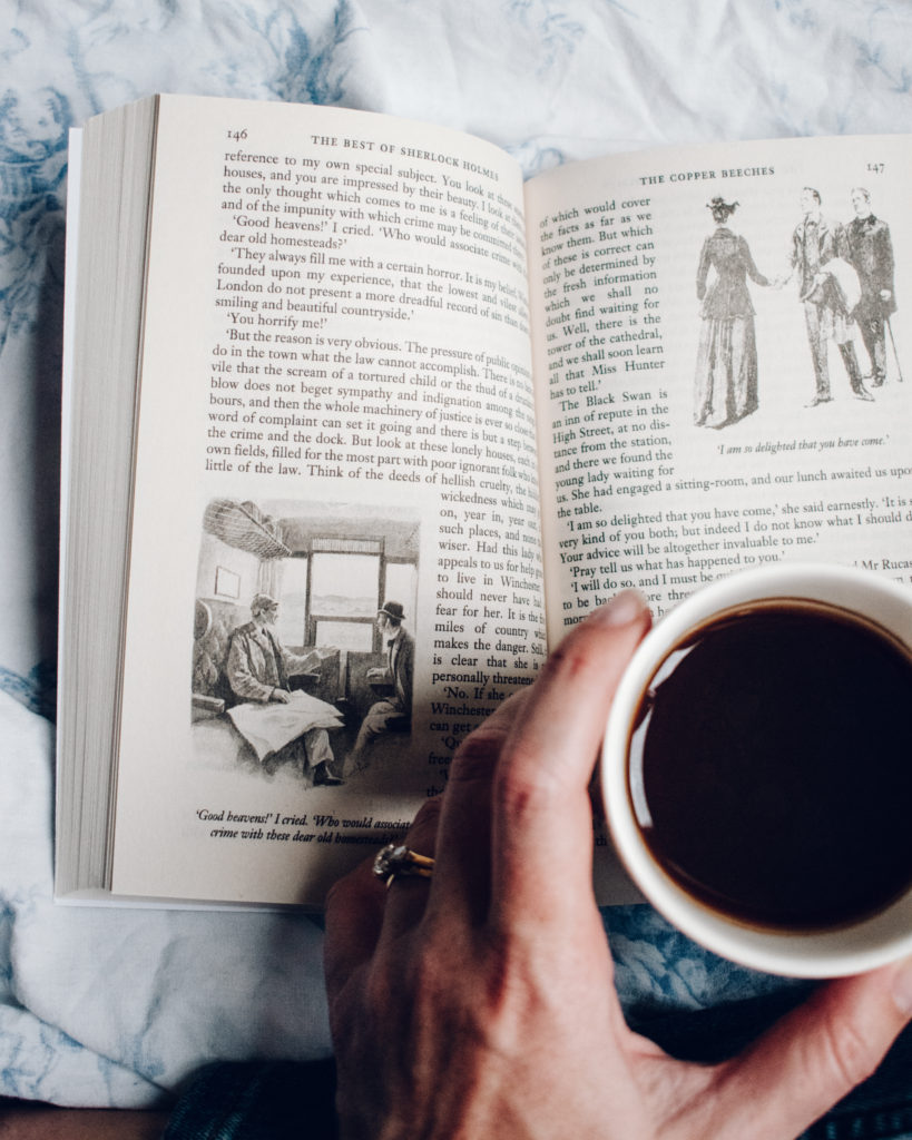 Literary London flat lay - woman drinking coffee and reading Sherlock Holmes