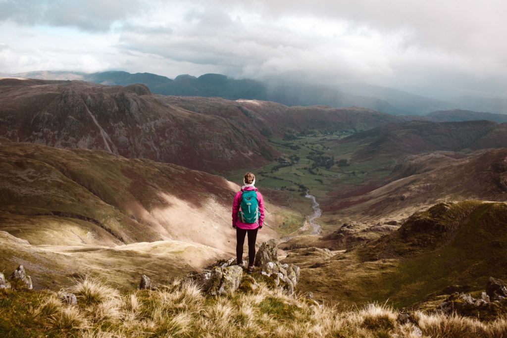 Woman hiking in the Lake District on Crinkle Crags in pink waterproof and green rucksack