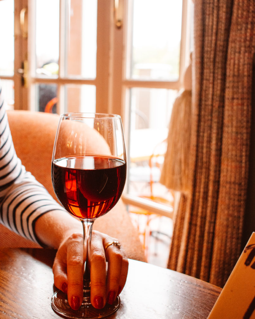 London Pubs - woman's hand holding glass of red wine at White Hard, Barnes