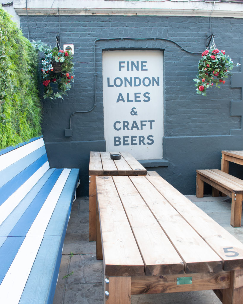 Rustic wooden tables and a painted sign at The Ship, Wandsworth