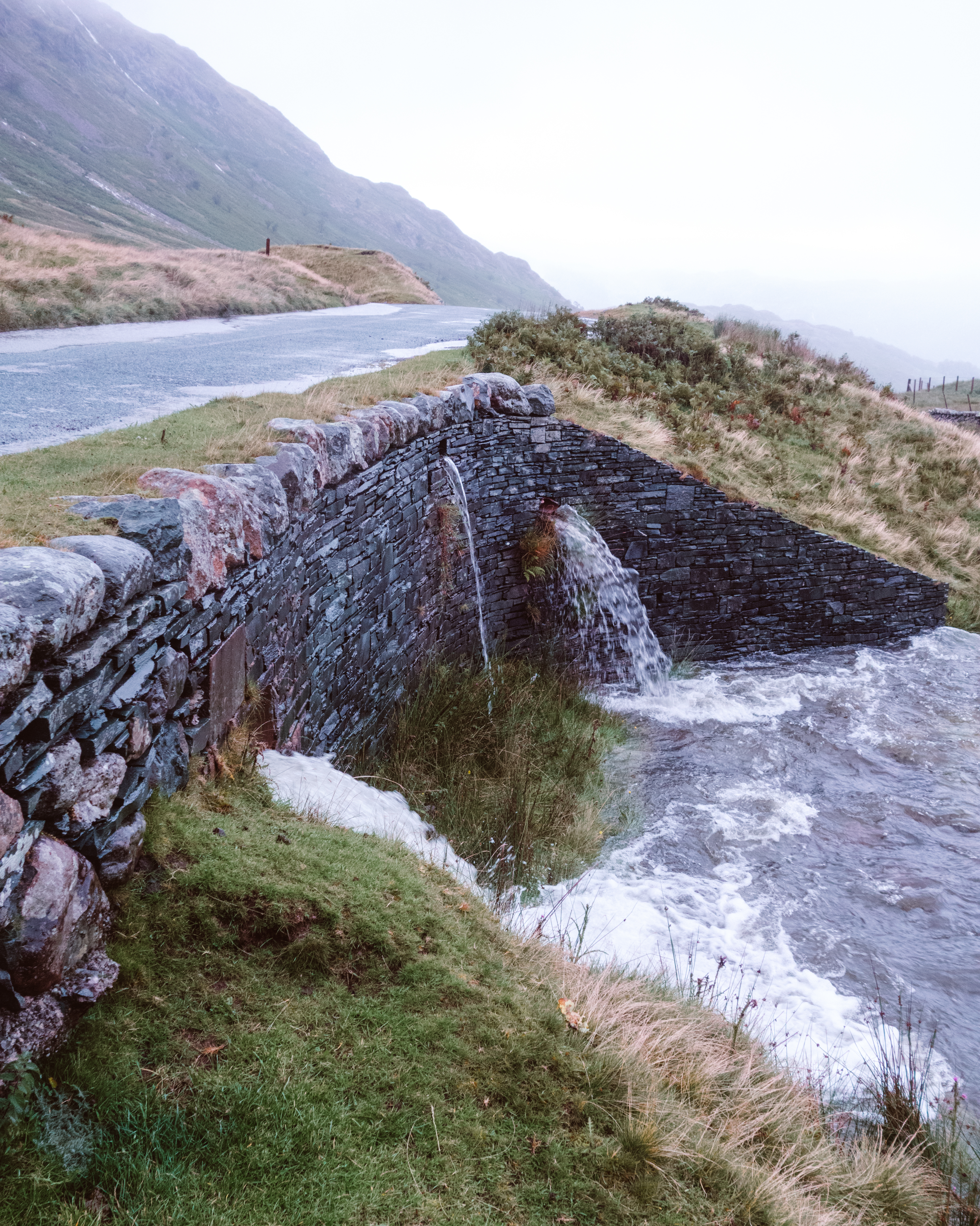 Rain pouring through a small stone bridge in the Lake District 