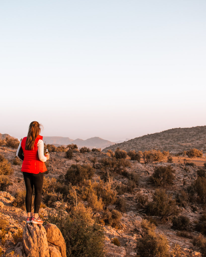 Woman in red gilet watching sunset from a camping spot on Jebel Akhdar