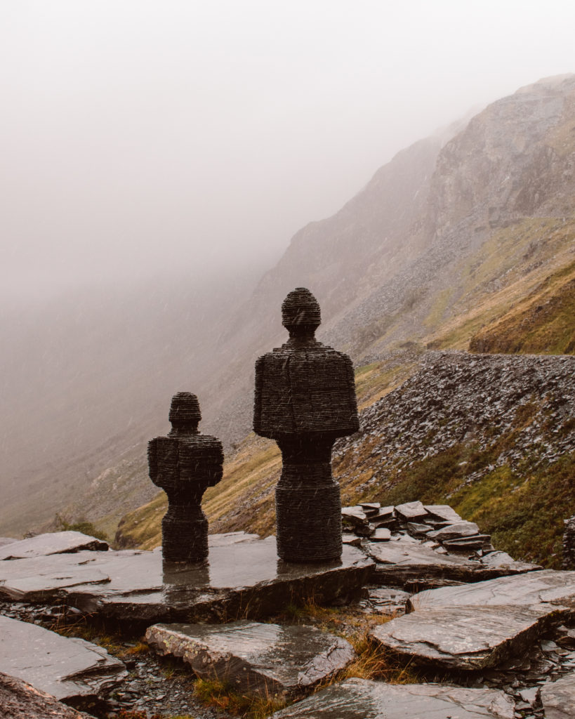 Slate statues of two people at Honister Pass on a wet, rainy day