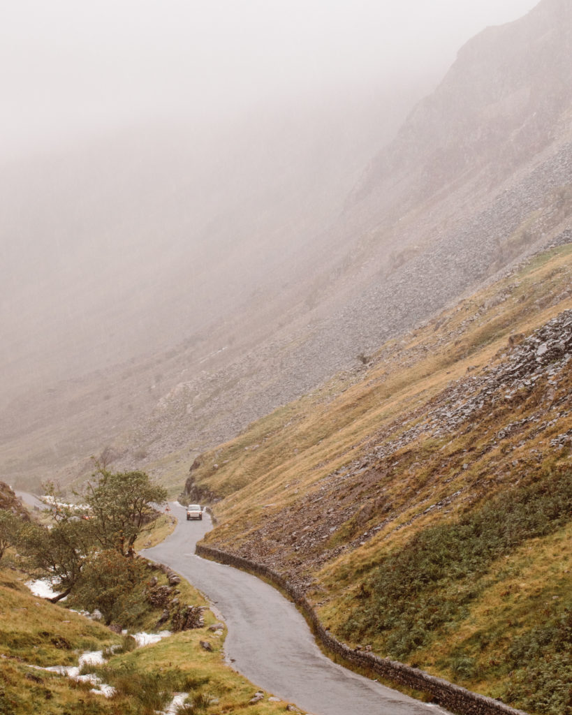 Wet road winding over Honister Pass on a foggy, rainy day 