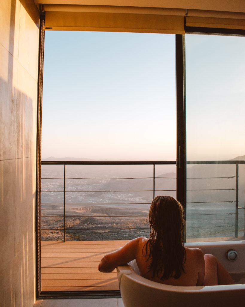 Woman in bathtub at The View, Jebel Shams, looking out over the town of Al Hamra