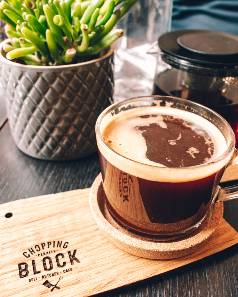 Glass of coffee presented on a wooden cleaver, at The Chopping Block, Penrith