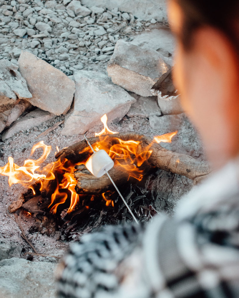 Woman toasting marshmallows over camp fire on Jebel Shams
