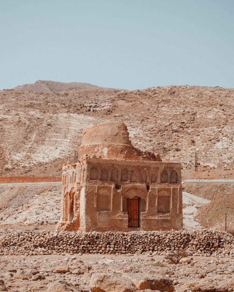 Semi ruined tomb in front of the rocky Eastern Hajar mountains, at the Ancient City of Qalhat, just outside Sur