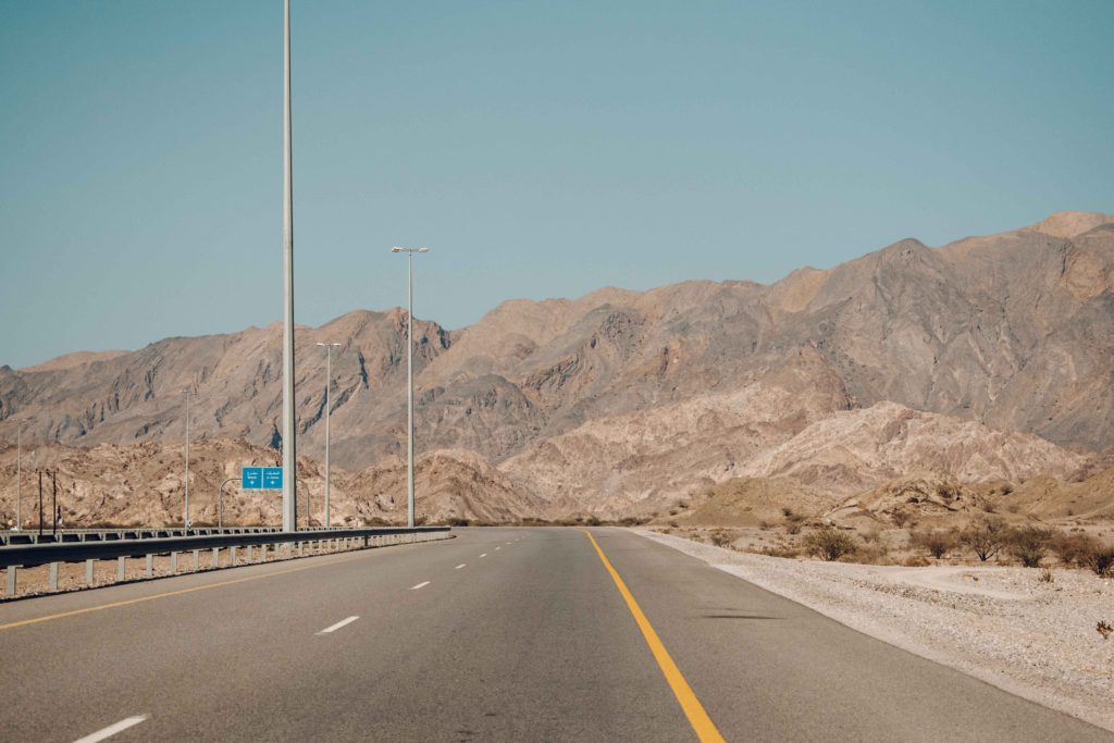 Empty stretch of Highway flanked by large Rocky Mountains - Highway 17 from Muscat to Sur