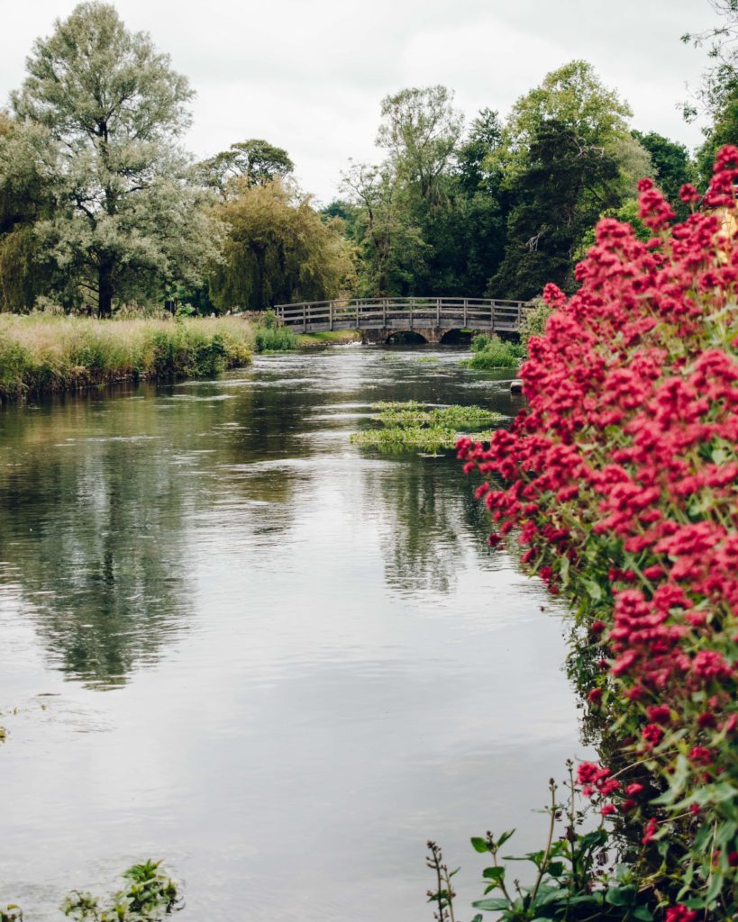 Small arched bridge over a calm river in Bibury, Cotswolds.