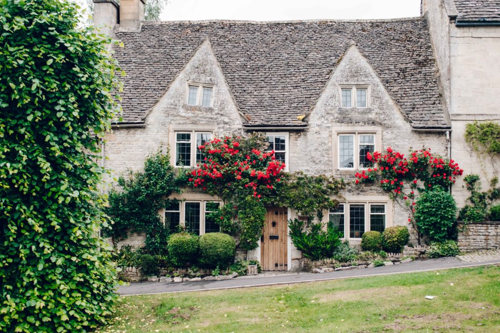 Bright red roses on an old stone cottage in Burford.