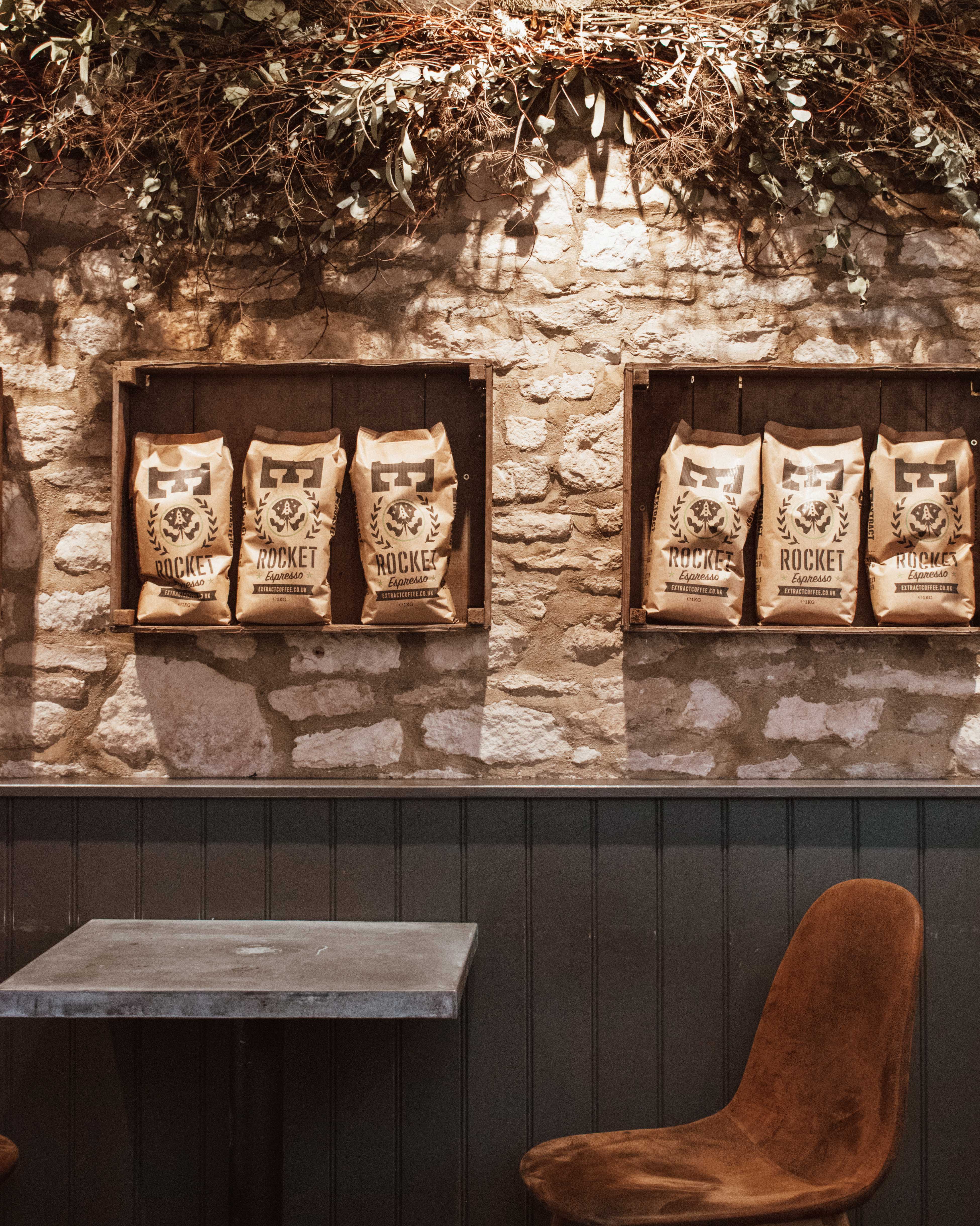 Bags of coffee in wooden crates on the stone wall in Lynwood Coffee, Burford.