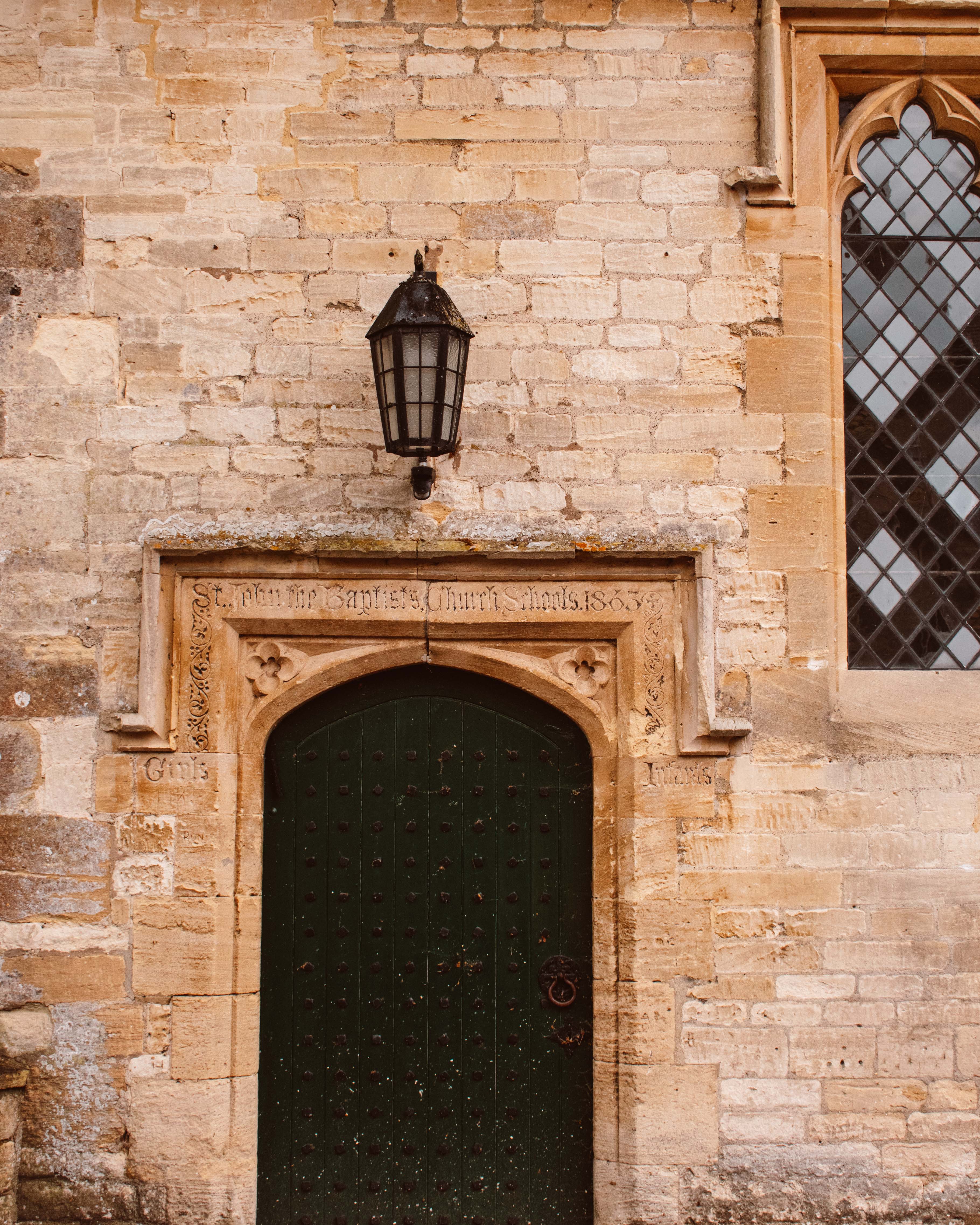 Carved stone archway over wooden door and stained glass window.