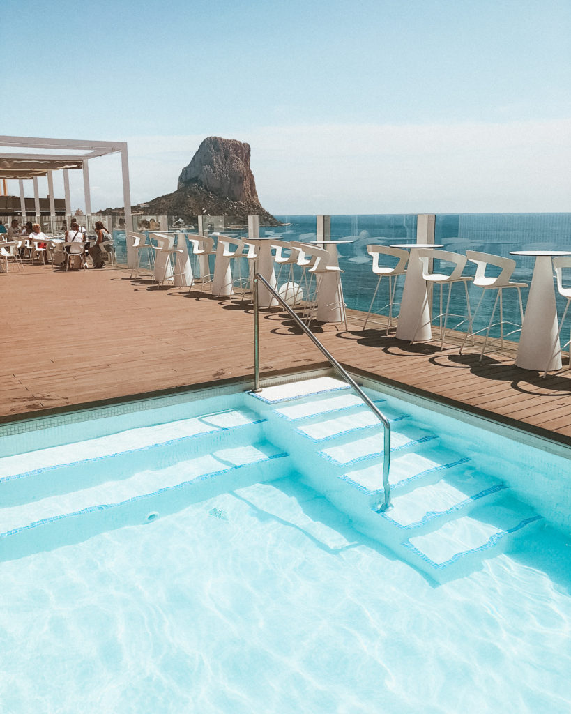 Pale blue swimming pool on rooftop of Hotel Bahia Calpe with views over Penon d'Ifach. 