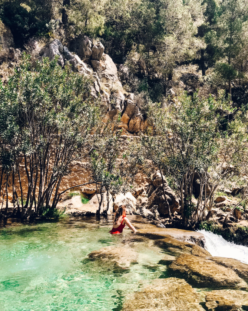 Woman in red swimsuit in green waters of Fonts de l'Algar.