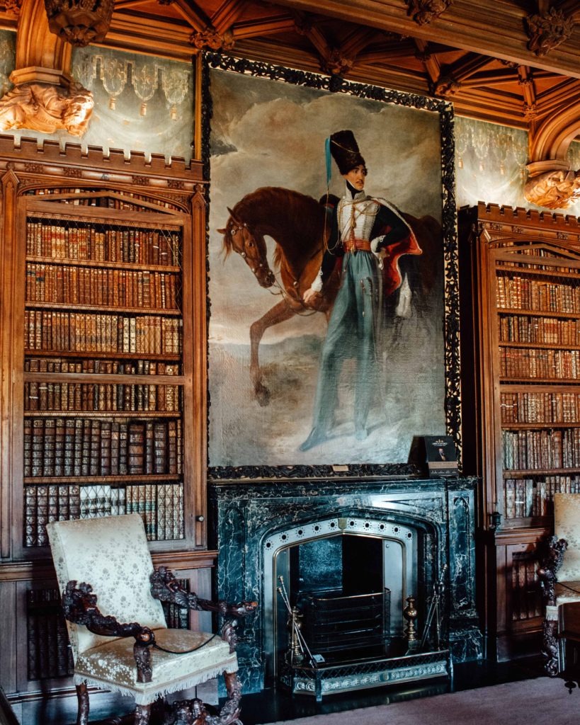 Book lined shelves either side of a large military painting and fireplace at Abbotsford, the home of Sir Walter Scott
