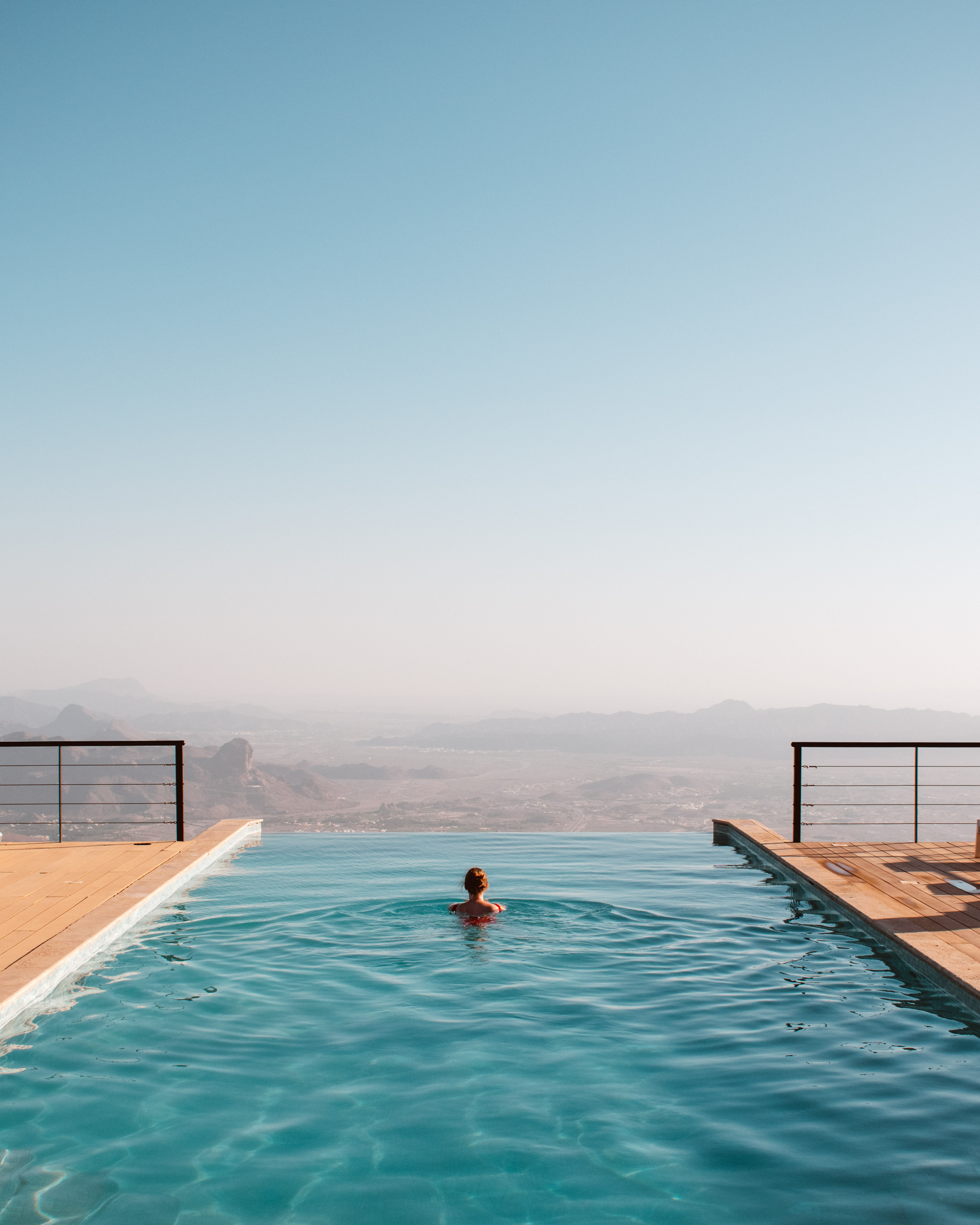 Woman swimming in infinity pool, in Oman. Oman's best hotels.