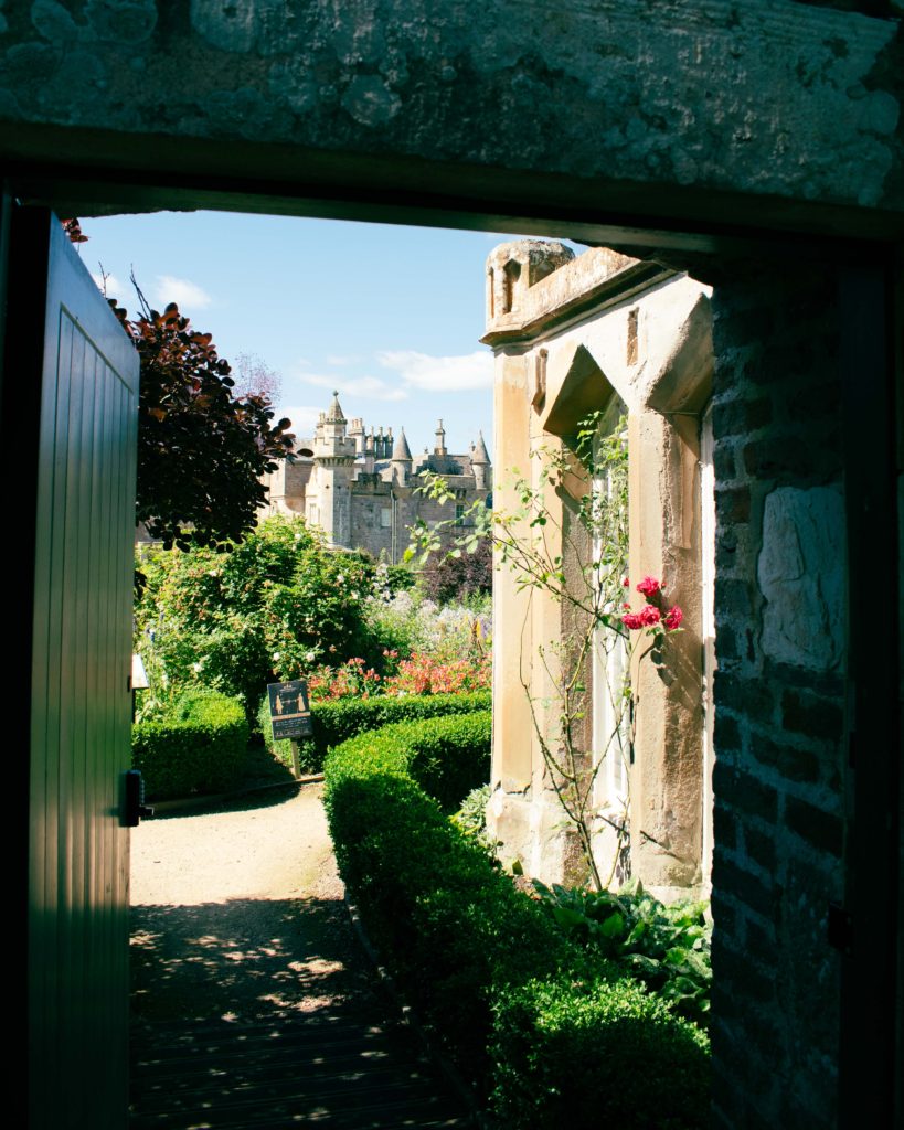 The turrets of at Abbotsford, the home of Sir Walter Scott, seen through a gateway into the formal gardens on a sunny day