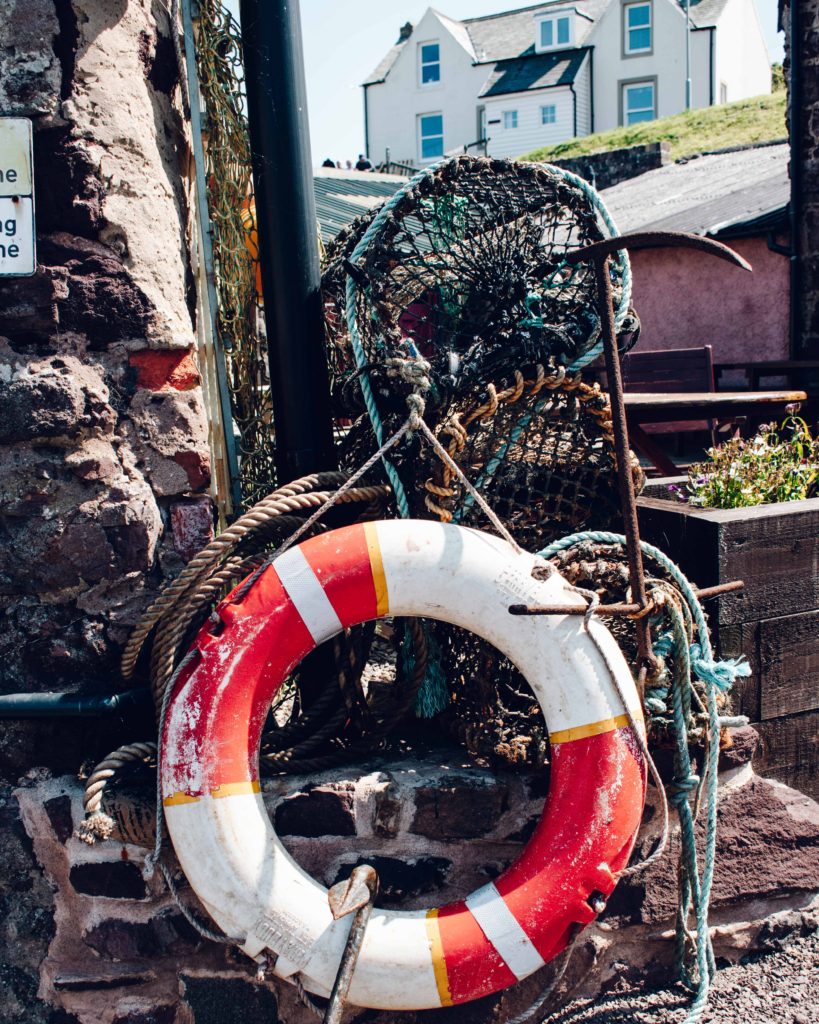 Red and white lifesaving ring and lobster pots at St Abbs