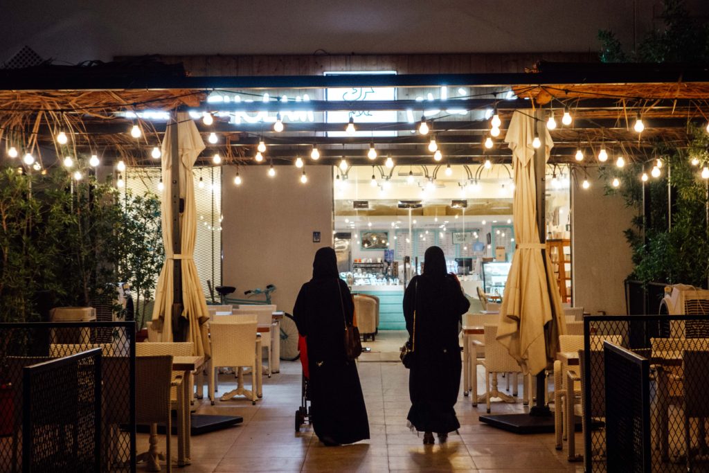 Two Omani ladies walking under fairy lights at Karak Gholam, Muscat