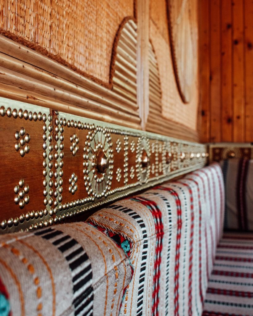 Woven cushions and brass studded wooden walls at the Tea House, Muscat