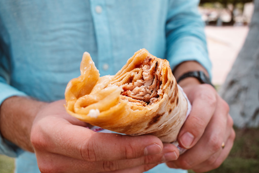 Man in a blue shirt holding a chicken shawarma from Turkish House, Muscat