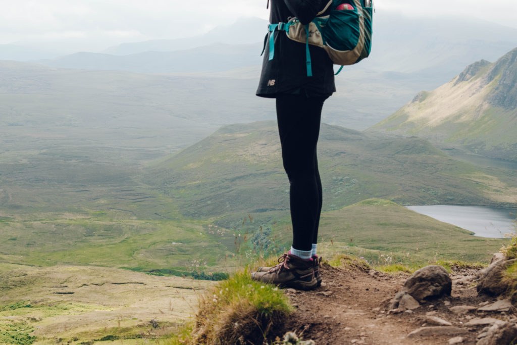 A woman in hiking kit looking out from the path through the Quiraing on Skye