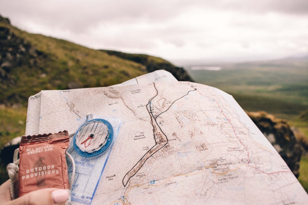 Woman holding a map of the Quiraing with a compass and energy bar