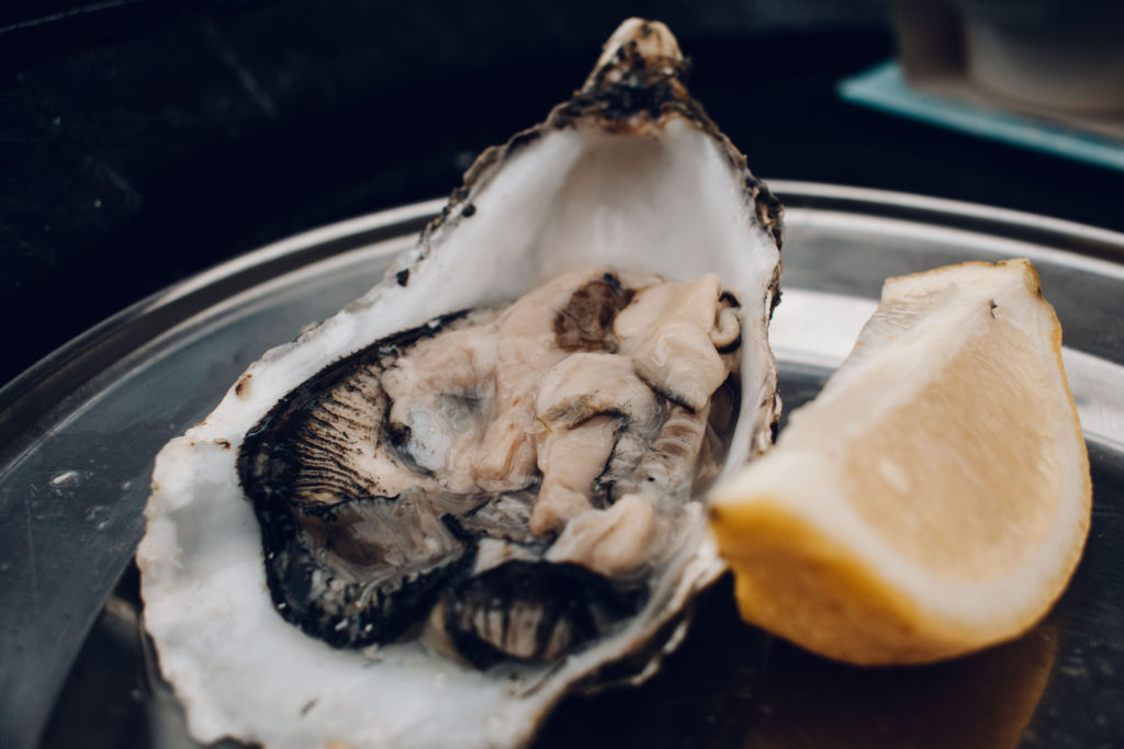 Large open oyster and slice of lemon on a metal tray at The Oyster Shed, Skye