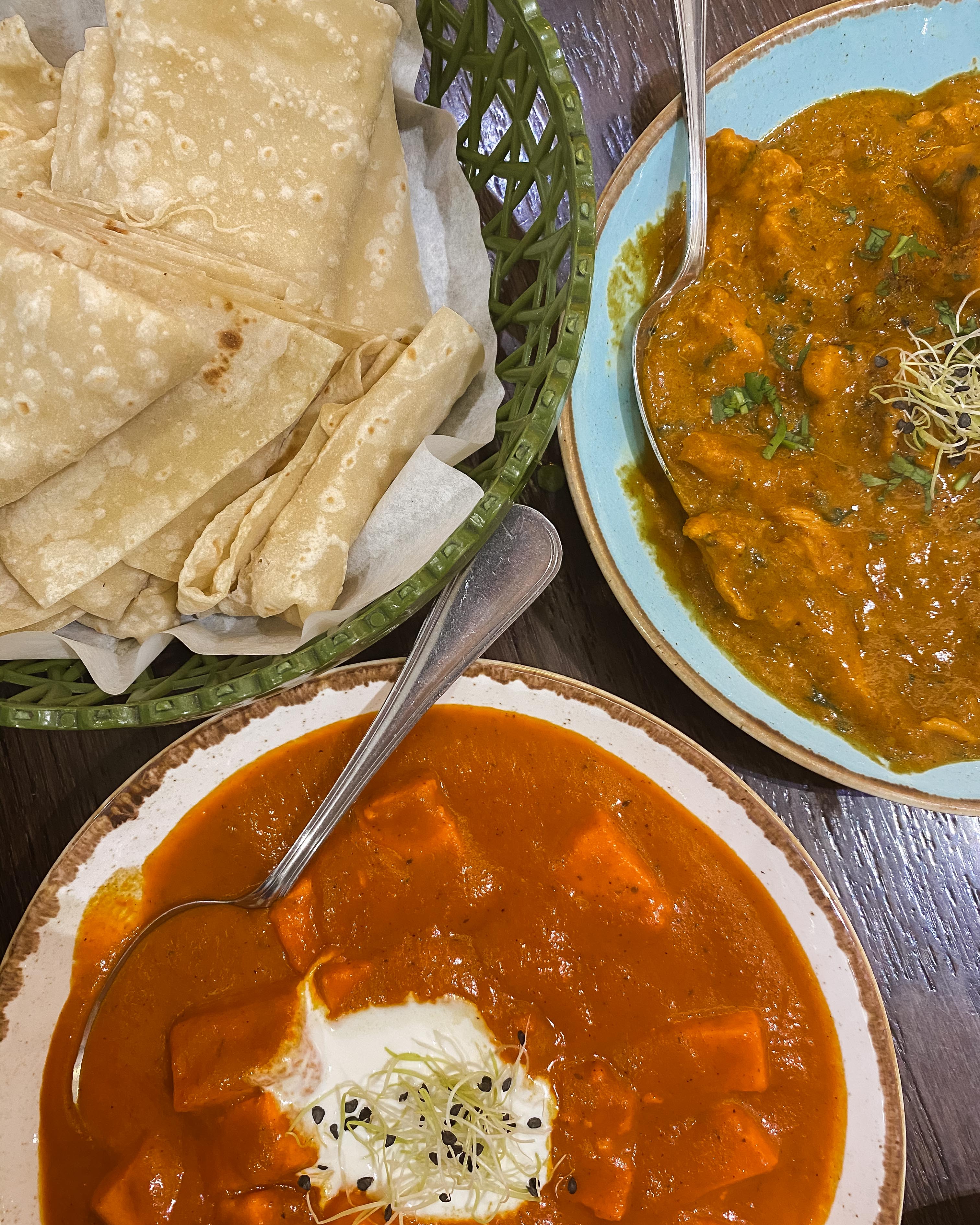 Curries in brightly coloured bowls and a basket of roti at Tuk Tuk, Muscat City Centre Mall