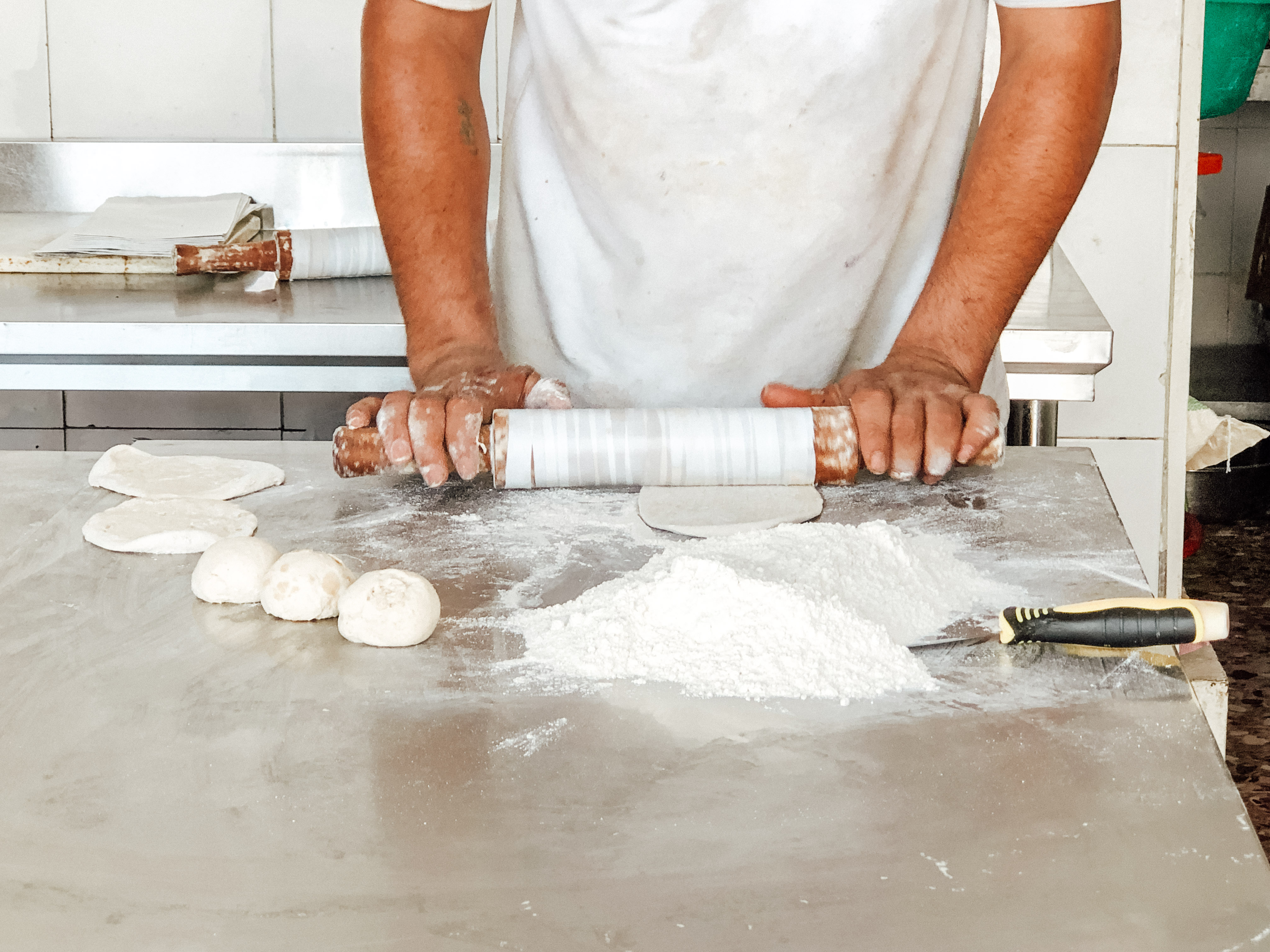 Man making out paratha with a rolling pin at Al Haikal Bakery, Muscat