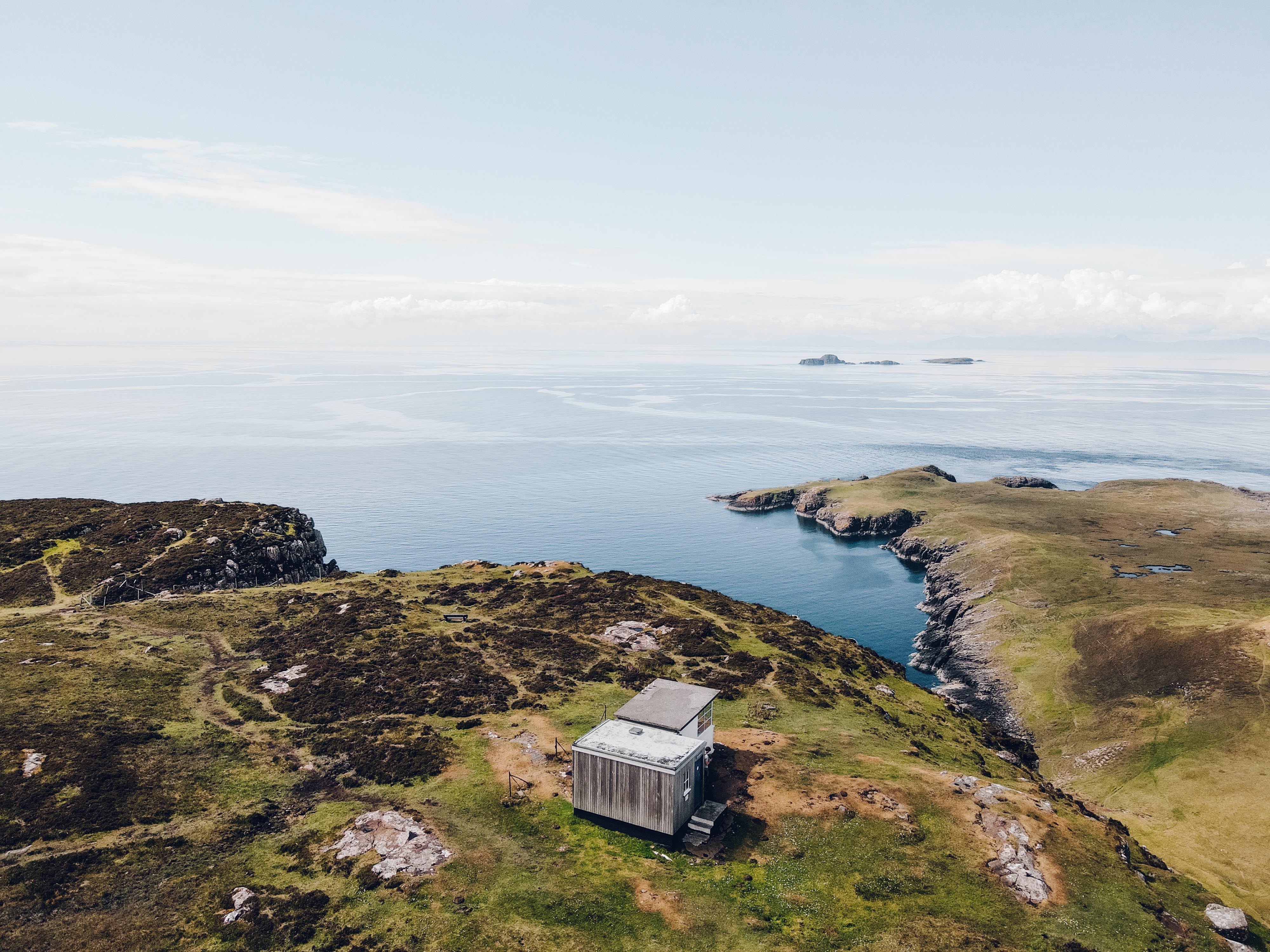 Aerial photo of a small hut perched on a sea cliff at Rubha Hunnish