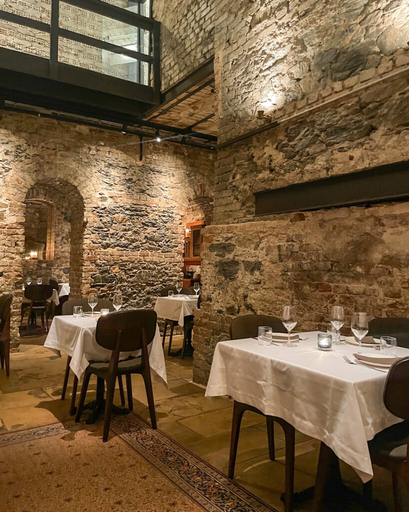 Exposed brick work and white tablecloth covered tables with glassware inside Aheste restaurant in Istanbul