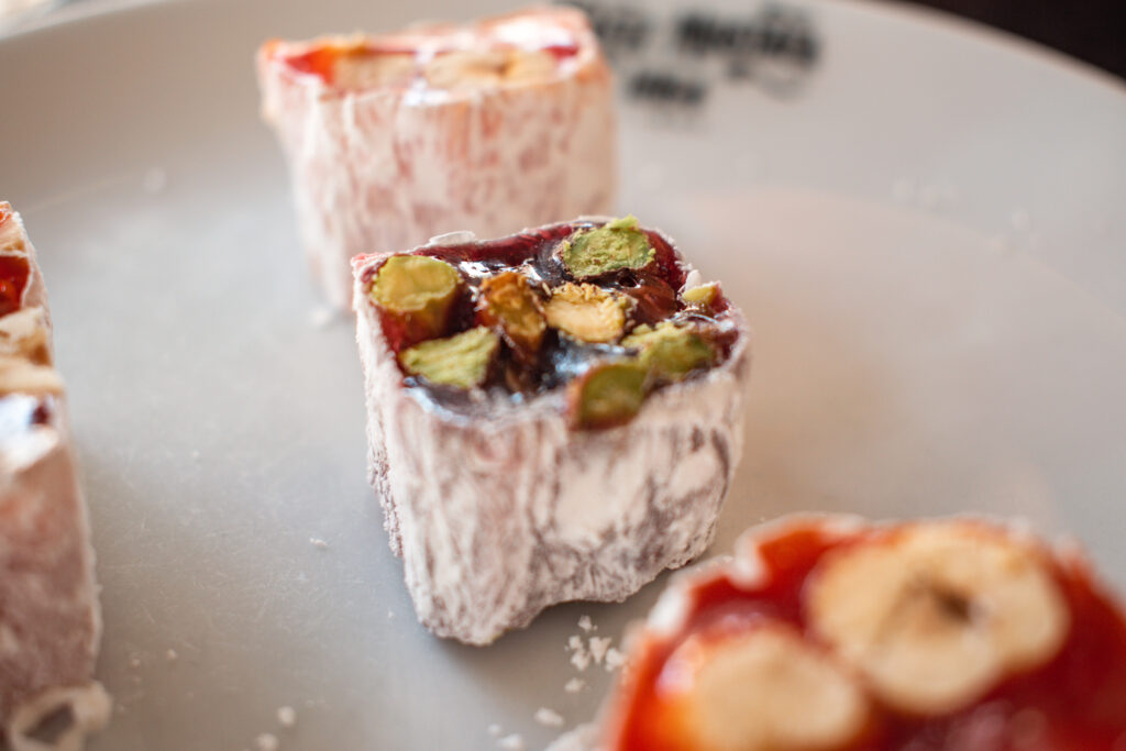 Three pieces of Turkish delight on a plate at Hafiz Mustafa, filled with pistachios