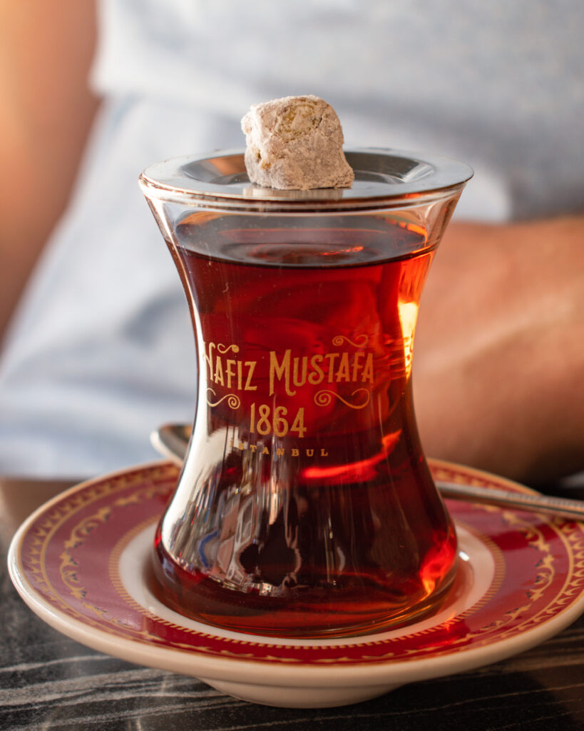 Small square of Turkish delight on a plate perched on top of a glass of Turkish cay from Hafiz Mustafa