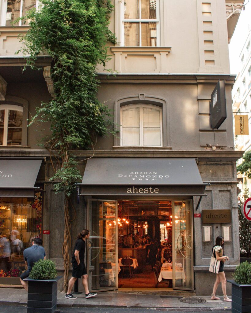 Warm lights and tables seen inside Aheste in Istanbul from outside on the street