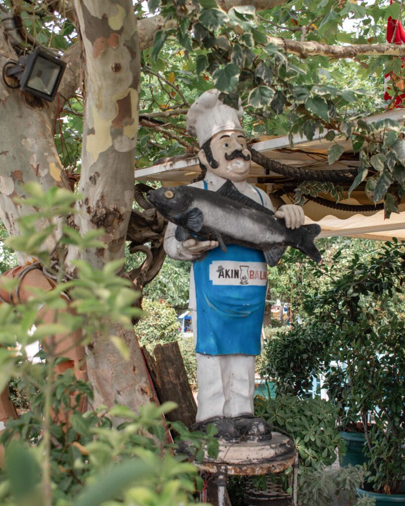 Wooden statue of man in chef's uniform holding a large fish