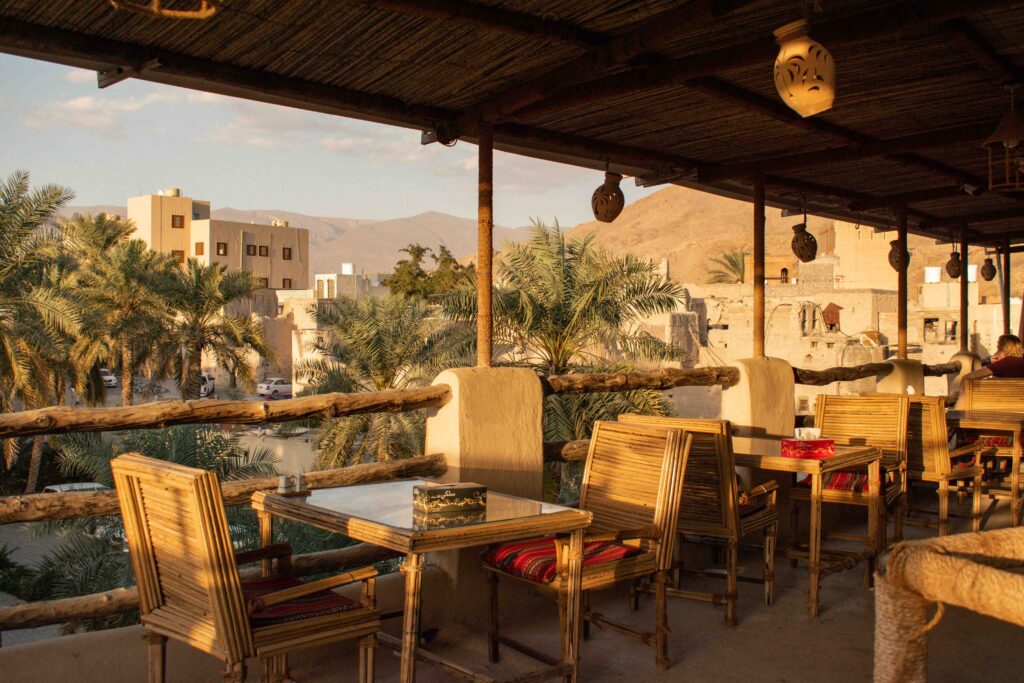 Terrace with wooden chair and tables at Nizwa Antique Inn in late afternoon sunshine
