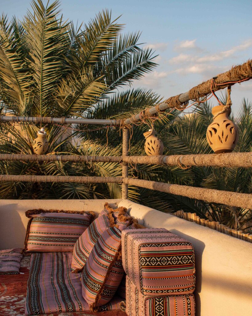 Majlis style seating cushions on terrace with terracotta hanging pots in late afternoon sunshine