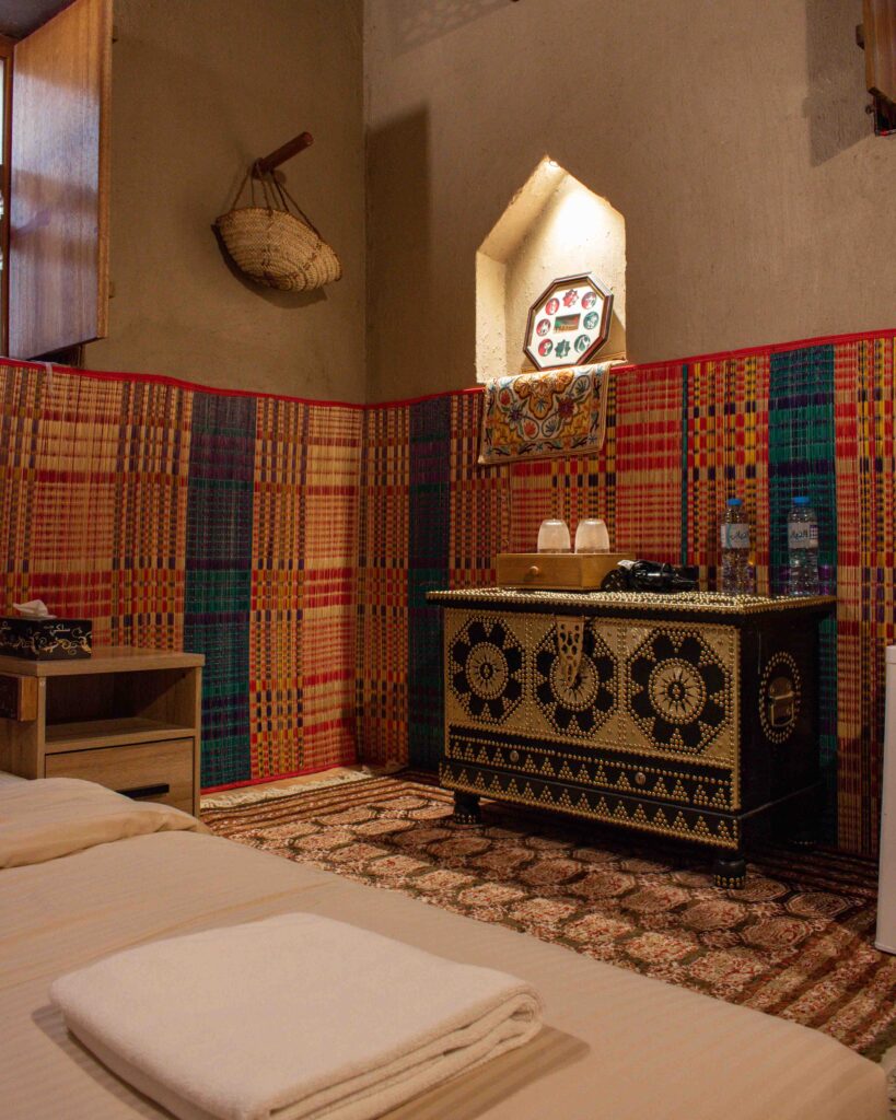 Gold studded wooden Omani tandoors chest behind mattress on floor in room at Nizwa Antique Inn