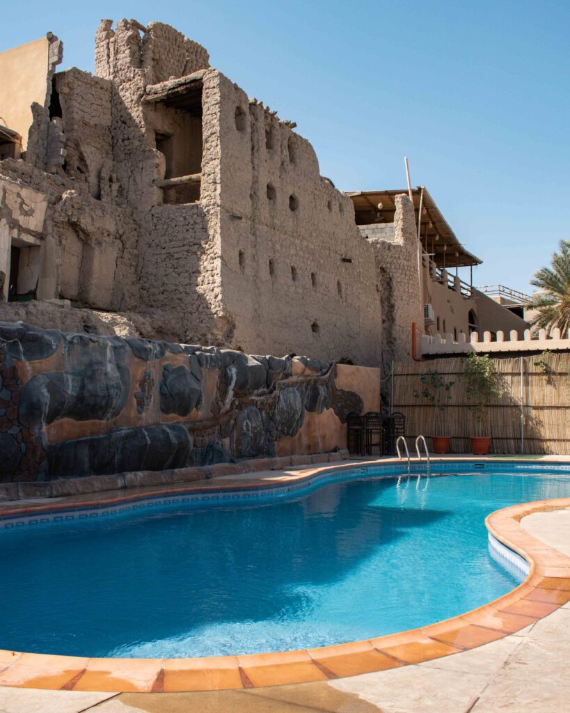 Empty blue swimming pool in front of semi ruined building in Nizwa, Oman