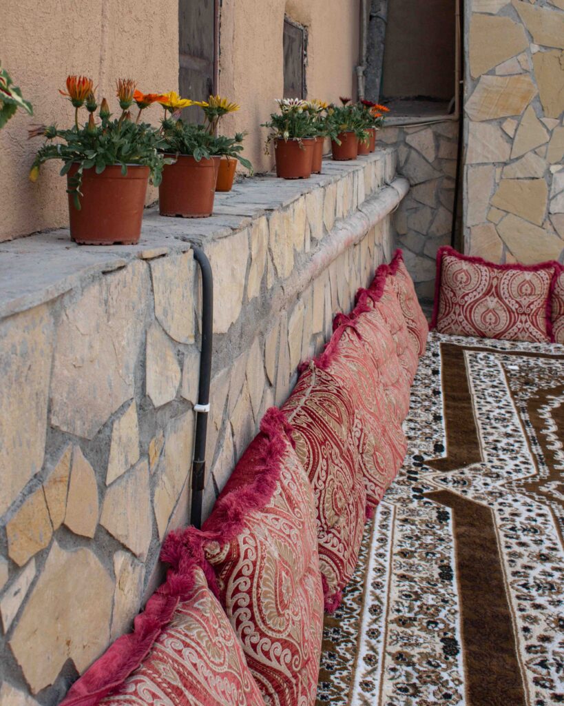 Low stone wall behind majlis style seating cushions and plant pots at Nizwa Antique Inn